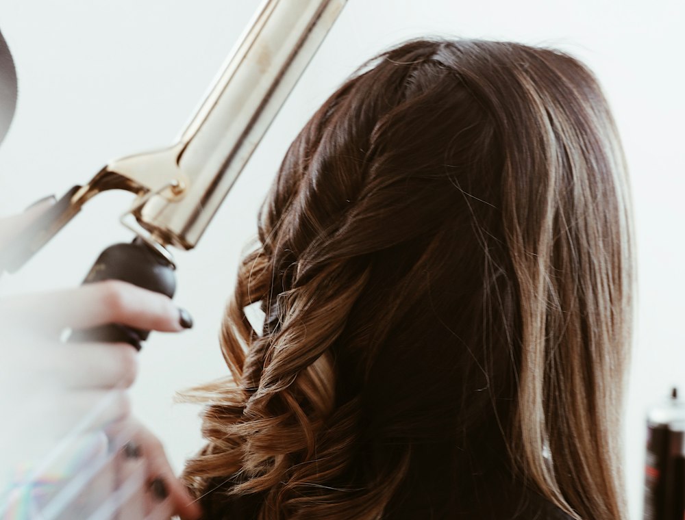 A stylist curling long hair with an iron